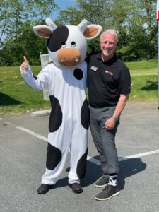 Brad Chivington, senior vice president of Carroll Independence and High’s, stands with a large cow mascot.